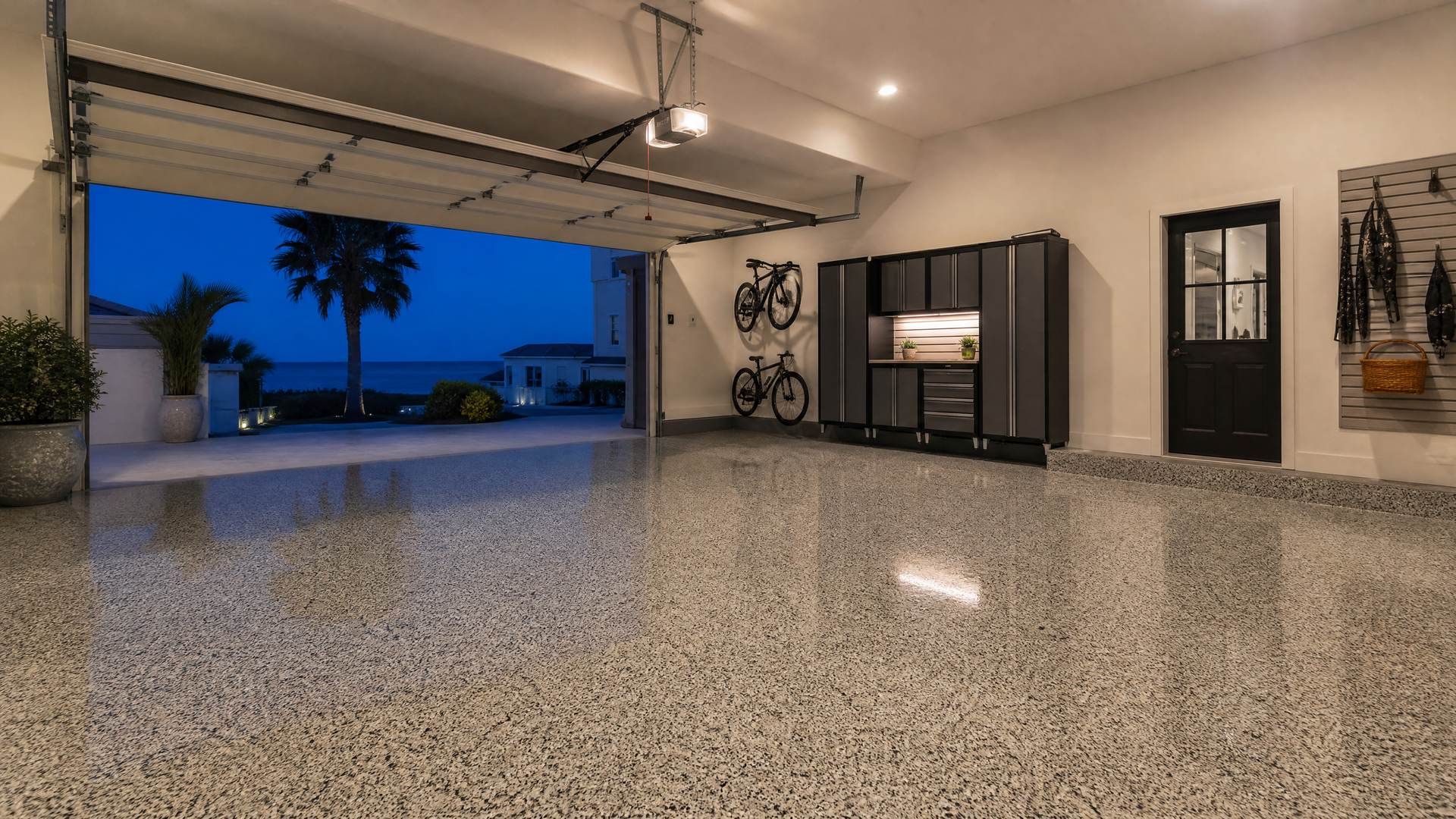 A garage open to a waterfront view at dusk with a speckled flake epoxy floor
