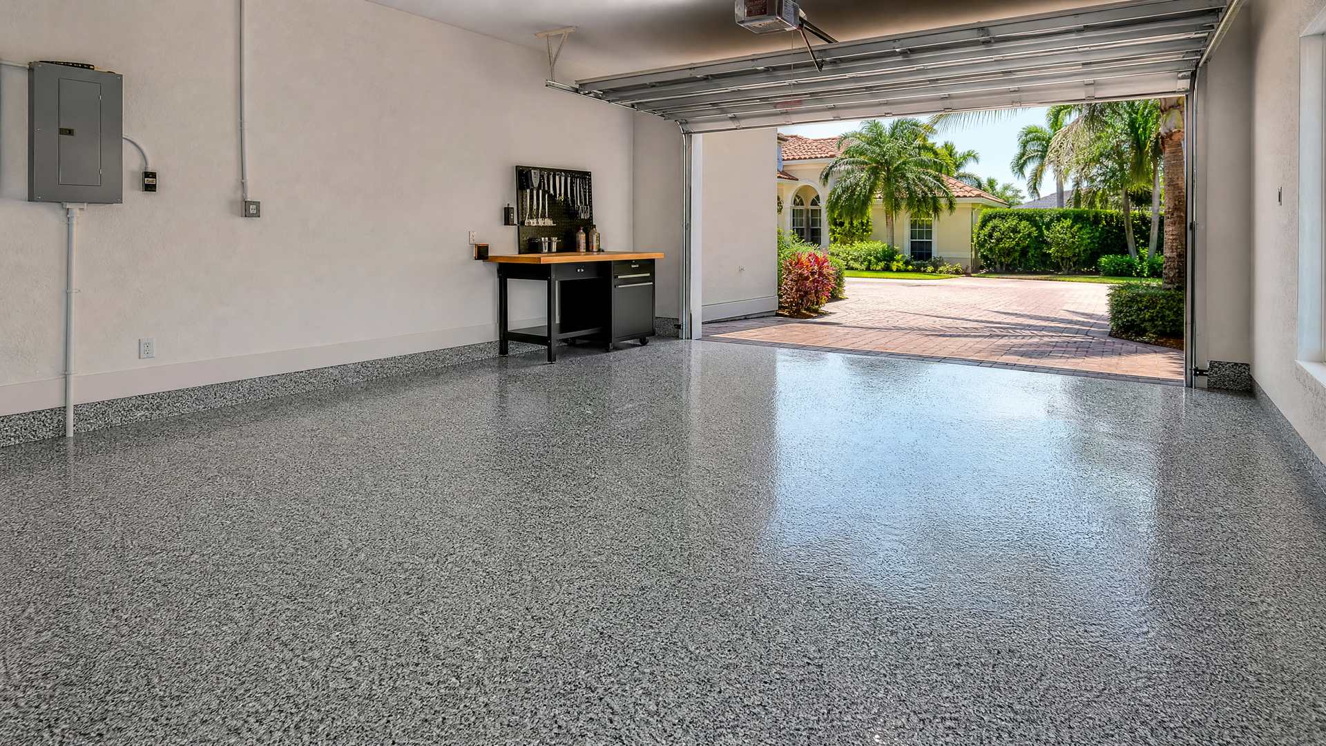 A Florida garage with a grey flake epoxy floor open to a Mediterranean-style home